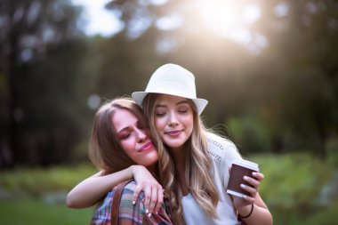 Yeşil parkta yürüyen iki genç kadın. Öğrenci kızlar konuşuyor. En iyi arkadaşlar