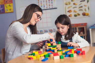 Öğretmen ve çocuk oyuncak yapı taşlarıyla oynuyorlar