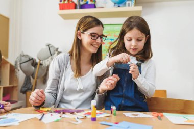 Anne ve çocuk birlikte zanaat yaparak vakit geçiriyorlar. 