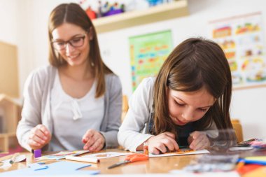 Anne ve çocuk birlikte ev ödevi yapıyorlar. 