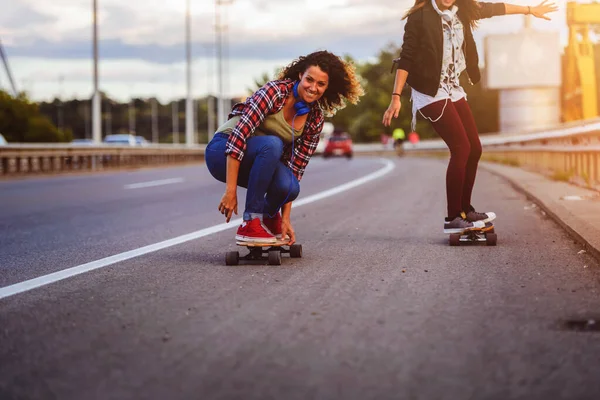 stock image happy young women riding on skateboards on city streets