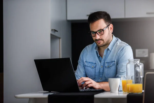 Stock image young man with a laptop working from home in the kitchen