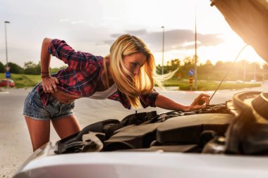 Kırık arabalı genç bir kadın yolda. 