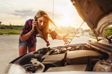 Kırık arabalı genç bir kadın yolda. 