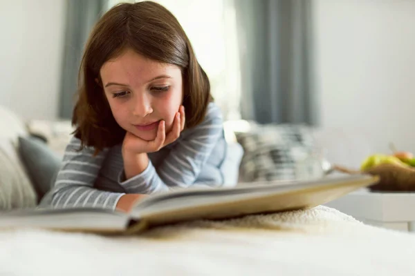 stock image beautiful little girl reading book on sofa 