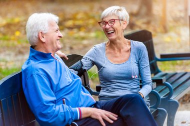 Gülümseyen son sınıf öğrencisi, aktif bir çift bankta oturmuş konuşuyor.
