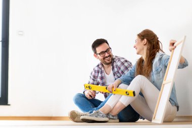 Güzel bir çift yeni boş bir daireye taşındılar. Cetvelle birlikte yerde oturuyorlar. Yer değiştirdikten sonra etkinlikler. Mülk yenileniyor.