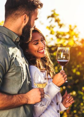 Genç çift üzüm bağında şarap içiyor. 