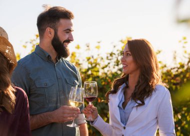 Genç çift üzüm bağında şarap içiyor. 