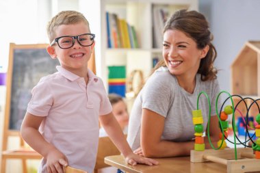 Anaokulunda renkli ahşap oyuncaklarla oynayan çocuklu anaokulu öğretmeni.