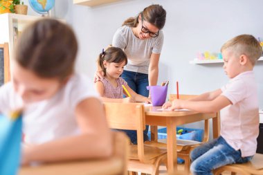 Anaokulunda kız öğrenci ve çocukla öğretmen.  