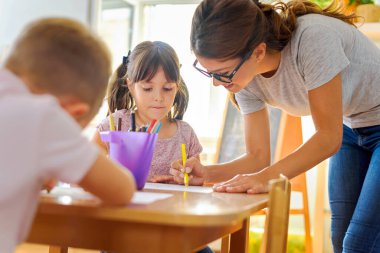 Öğretmen öğrencilerin resim çizmesine yardım ediyor 