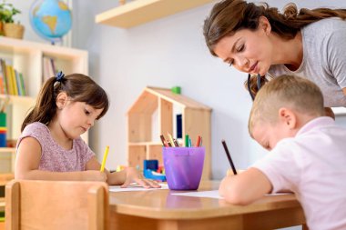 Öğretmen öğrencilerin resim çizmesine yardım ediyor 