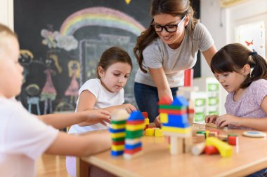 Öğretmen anaokulunda çocuklarla ahşap bloklar kullanarak oynuyor.