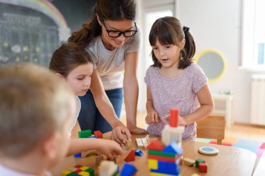 Öğretmen anaokulunda çocuklarla ahşap bloklar kullanarak oynuyor.