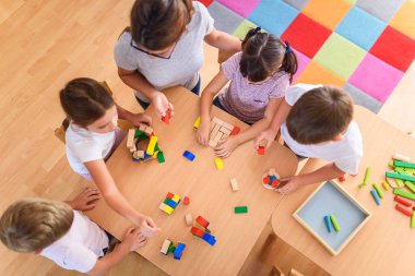 Öğretmen anaokulunda çocuklarla ahşap bloklar kullanarak oynuyor.