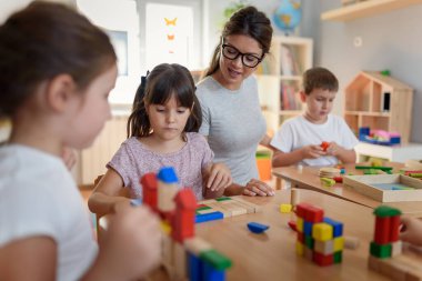Öğretmen anaokulunda çocuklarla ahşap bloklar kullanarak oynuyor.