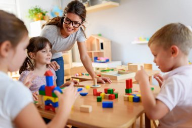 Öğretmen anaokulunda çocuklarla ahşap bloklar kullanarak oynuyor.