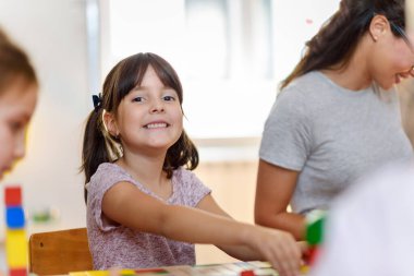 Anaokulunda renkli ahşap oyuncaklarla oynayan çocuklu anaokulu öğretmeni.