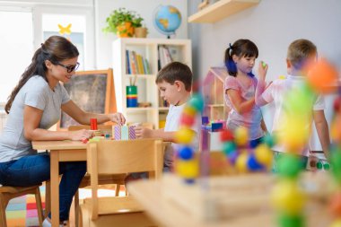 Öğretmen anaokulunda çocuklarla ahşap bloklar kullanarak oynuyor.