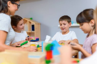 Öğretmen anaokulunda çocuklarla ahşap bloklar kullanarak oynuyor.
