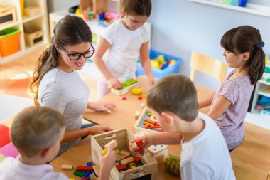 Öğretmen anaokulunda çocuklarla ahşap bloklar kullanarak oynuyor.