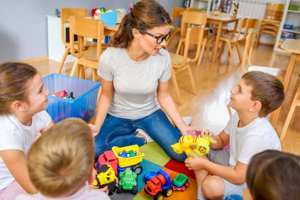 Kindergärtnerin Spricht Mit Kindergruppe Die Kindergarten Auf Dem Fußboden Sitzt — Stockfoto