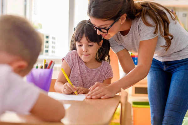 stock image teacher helping students to draw 