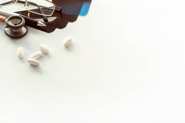 Tıbbi belgeler, çizelgeler, gözlükler ve steteskopla birlikte doktorun çalışma masası.