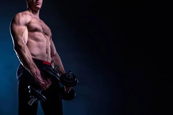 黒を背景にダンベルを持つ筋肉質の男 — ストック写真