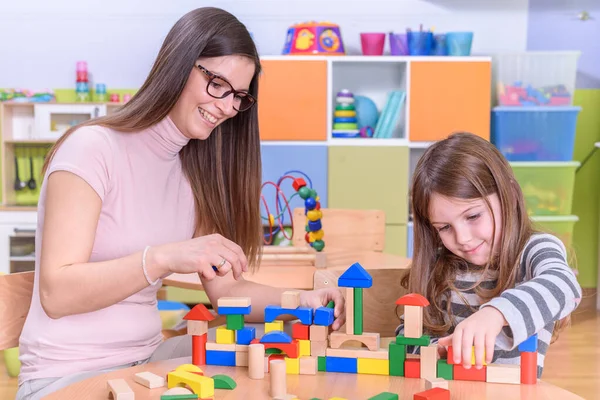 先生と女の子は学校でおもちゃのブロックで遊んでいます — ストック写真