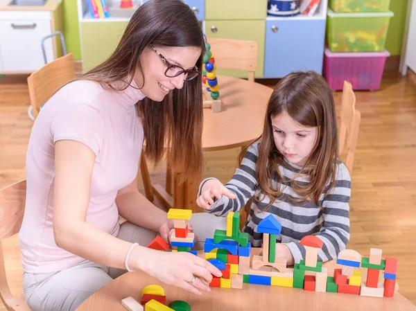 stock image teacher and girl playing with toy blocks at school