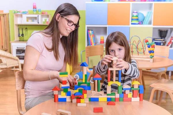 先生と女の子は学校でおもちゃのブロックで遊んでいます — ストック写真