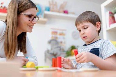 Gururlu bir anne oğluna bakıyor. Didactic oyunlar oynuyor, öğreniyor.