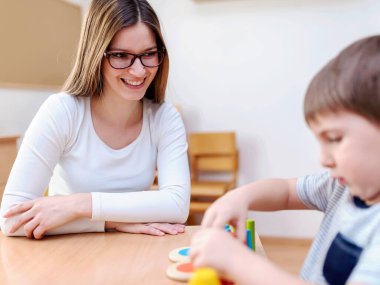 Gururlu bir anne oğluna bakıyor. Didactic oyunlar oynuyor, öğreniyor.