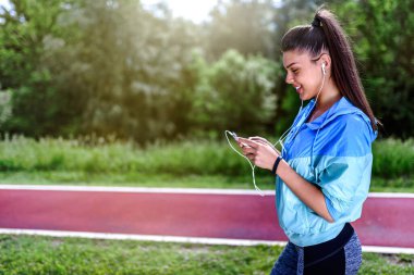 Genç sporcu kadın kulaklıkla müzik dinliyor. 