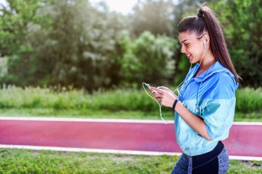 Genç sporcu kadın kulaklıkla müzik dinliyor. 