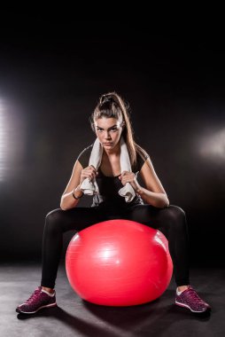 Siyah arka planda topu olan genç bir kadın.