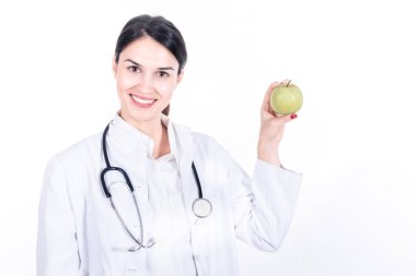 Beyaz arka planda steteskoplu ve elmalı genç bayan doktor.