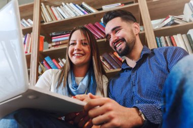 Kütüphanede dizüstü bilgisayarla çalışan öğrenci çift.