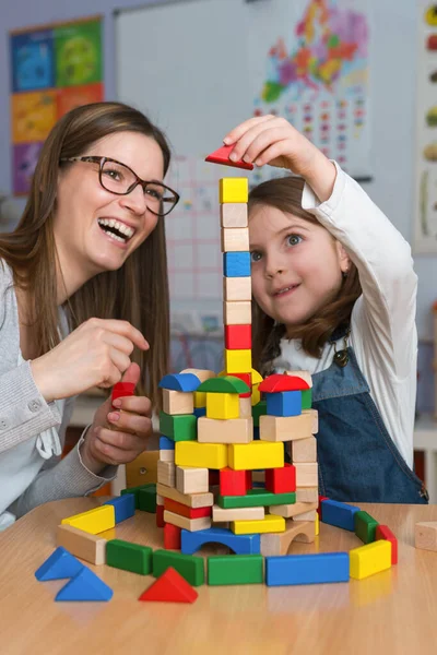 happy teacher and kid playing with toy blocks at home