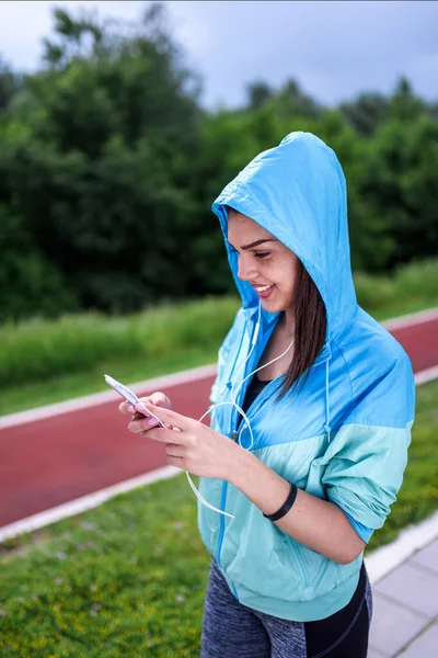 Genç sporcu kadın kulaklıkla müzik dinliyor. 