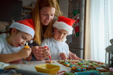 Anne ve çocuklar Noel için kurabiye pişiriyor.