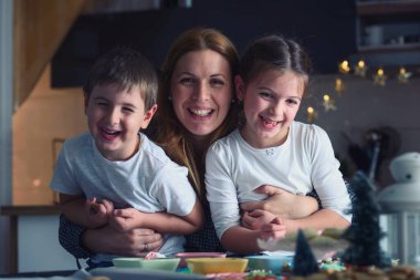 Anne ve çocuklar Noel için kurabiye pişiriyor.