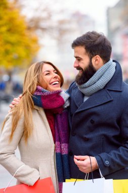 Alışveriş torbalarıyla gülümseyen romantik çift