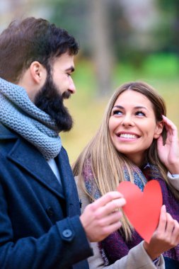 Kırmızılı çift parkta poz veriyor. 