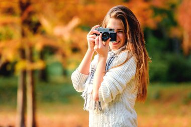 Park yerinde geçmişe dönük kamerası olan güzel bir genç kadının portresi.