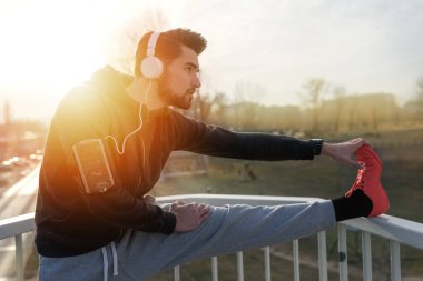 Egzersizden önce koşan ve dışarıda müzik dinleyen bir koşucu.