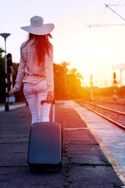 Bagajı olan genç bir kadın gün ışığında yürüyor. Seyahat arkaplanı.