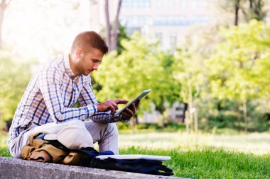 Ekose takım elbiseli, tablet kullanan sıradan bir genç.